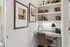 Charming home office nook with elegant decor, featuring artful wall frames, stylish shelving, and a cozy workspace with a lamp.
