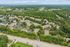 Aerial view of a charming residential community surrounded by lush greenery and providing ample parking space.