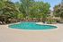 Inviting outdoor pool area surrounded by lush greenery and sun loungers, perfect for relaxation and leisure.