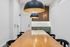 Modern meeting room with elegant wood table, chic black pendant lights, and stylish white walls featuring vertical wood panel accent.