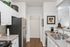 Charming kitchen with elegant white cabinetry, stainless steel appliances, and a cozy hallway view.