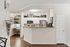 Elegant apartment kitchen with sleek stainless steel appliances, white cabinetry, and a cozy office nook enhancing functionality and style.