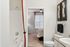 Inviting bathroom with modern fixtures, elegant white tiles, and a soft glimpse into a cozy, sunlit bedroom.