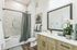 Elegant bathroom with modern fixtures, a large mirror, and stylish marble tiled shower.