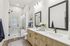 Elegant bathroom featuring a modern glass-enclosed shower, sleek dual vanity with black fixtures, and luxurious marble accents.