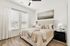 Bright and airy bedroom featuring a cozy bed with elegant bedding, large windows with natural light, and chic decor.