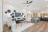 Bright open-concept living and dining area with modern decor, elegant wooden flooring, and stylish kitchen in the background.