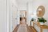 Bright and inviting hallway leading to a stylish open-plan living area, featuring elegant decor, wooden flooring, and modern lighting.