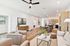 Inviting open-concept living room with elegant furnishing, featuring plush seating, modern art, and a sleek kitchen with wood accents.