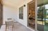 Inviting apartment patio with cozy table and chairs, leading into a stylishly decorated living room with warm lighting and a scenic outdoor view.