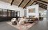 Modern lounge area with high ceilings, cozy fireplace, and elegant seating arrangement on a decorative rug.