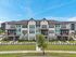 Charming modern row of townhouses with elegant design, lush greenery, and striking architectural details under a clear blue sky.
