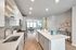 Modern kitchen with sleek countertops, stainless steel appliances, and open layout leading to a bright living room. Stylish decor and ample lighting create a warm, inviting atmosphere.