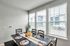 Bright dining area with large windows, featuring a chic black table set for four, accented with elegant decor and natural light.