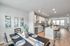 Bright and modern open-concept dining and kitchen area with sleek cabinetry, stainless steel appliances, and elegant decor, leading into a spacious living room with large windows.