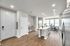 Modern apartment interior with open-plan layout featuring a sleek kitchen island, stainless steel appliances, and bright dining area with large windows.