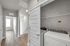 Bright hallway with elegant wood flooring leading to a cozy laundry area featuring modern washer and dryer units.
