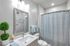 Elegant bathroom with modern fixtures, a stylish mirror, and soothing color palette, featuring plush towels and vibrant plant decor.