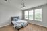 Bright and inviting bedroom with modern ceiling fan, large windows, and elegant wood flooring, perfect for relaxation.
