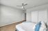 Modern bedroom with sleek ceiling fan and ample natural light, featuring stylish doors and a plush bed.