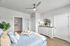 Bright and inviting bedroom featuring a stylish bed with cozy pillows, sleek dresser, and modern ceiling fan, complemented by soft natural light.
