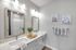 Elegant modern bathroom with dual sinks, stylish mirrors, decorative plants, and soft lighting for a serene atmosphere.