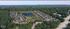 Aerial view of a beautifully designed apartment community with multiple buildings surrounding a scenic lake featuring fountains, nestled within lush greenery.
