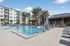Luxurious apartment complex with a stunning outdoor pool area, surrounded by palm trees and modern amenities.