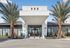 Elegant modern apartment entrance with lush palm trees and sleek architecture, exuding luxury and style.