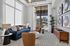 Modern living room with large windows, vibrant blue sofa, accent chairs, stylish decor, and lush greenery offering a bright and inviting atmosphere.