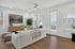 Bright and modern living room showcasing elegant hardwood floors, cozy seating, and abundant natural light through large windows.