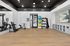 Contemporary fitness room featuring sleek exercise equipment, colorful stability balls, and stylish storage solutions on polished wooden floors.