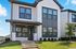 Charming two-story white house with modern gray accents, large windows, and inviting front entrance surrounded by well-maintained landscaping.