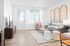 Bright and inviting living room with modern decor, featuring a chic gray sofa, stylish art pieces, and abundant natural light from large windows.