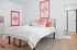 Bright and inviting bedroom with colorful artwork, elegant double bed with plush pillows, and en-suite bathroom showcasing modern design.
