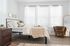 Bright and airy bedroom with modern decor, featuring a cozy bed, stylish brown chair, and elegant floor-length mirror.