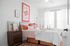 Bright and inviting bedroom with modern decor, featuring a cozy bed with vibrant cushions, stylish artwork, and ample natural light streaming through large windows.