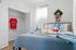 Charming bedroom with soft blue bedding, open closet, and vibrant decor including a wreath and playful pillows, inviting relaxation.