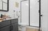 Modern bathroom featuring sleek black cabinetry, glass-enclosed shower, and elegant decor accents on granite countertop.