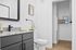 Sleek and modern bathroom with granite countertop, stylish black fixtures, and an inviting open closet space.