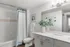 Bright and modern bathroom with a sleek white vanity, a bath-shower combination, and minimalist decor.