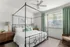 Bright and airy bedroom with a stylish canopy bed, natural light streaming through large windows, and tasteful decor.