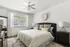 Well-lit bedroom with plush bedding, decorative pillows, large window, and modern furnishings.