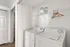 Bright laundry nook with washer, dryer, and tidy shelving in a contemporary apartment.