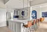 Contemporary kitchen with sleek white cabinets, blue backsplash, and stylish pendant lighting.