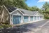Row of stylish garages with blue doors surrounded by lush greenery.