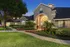Beautifully lit entrance of a residential building with lush landscaping and a curved pathway.