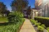 Charming garden walkway leading to a tranquil residential entrance with vibrant greenery.