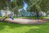 Inviting playground with swings and slides, surrounded by lush greenery and modern townhomes.