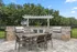 Stylish outdoor patio featuring a dining set with two stainless steel grills surrounded by lush greenery.